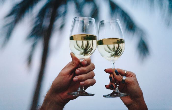Couple raising a toast under palm trees